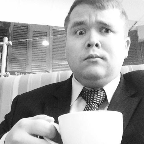 Ben Mackin holding a coffee cup while making a strange face.